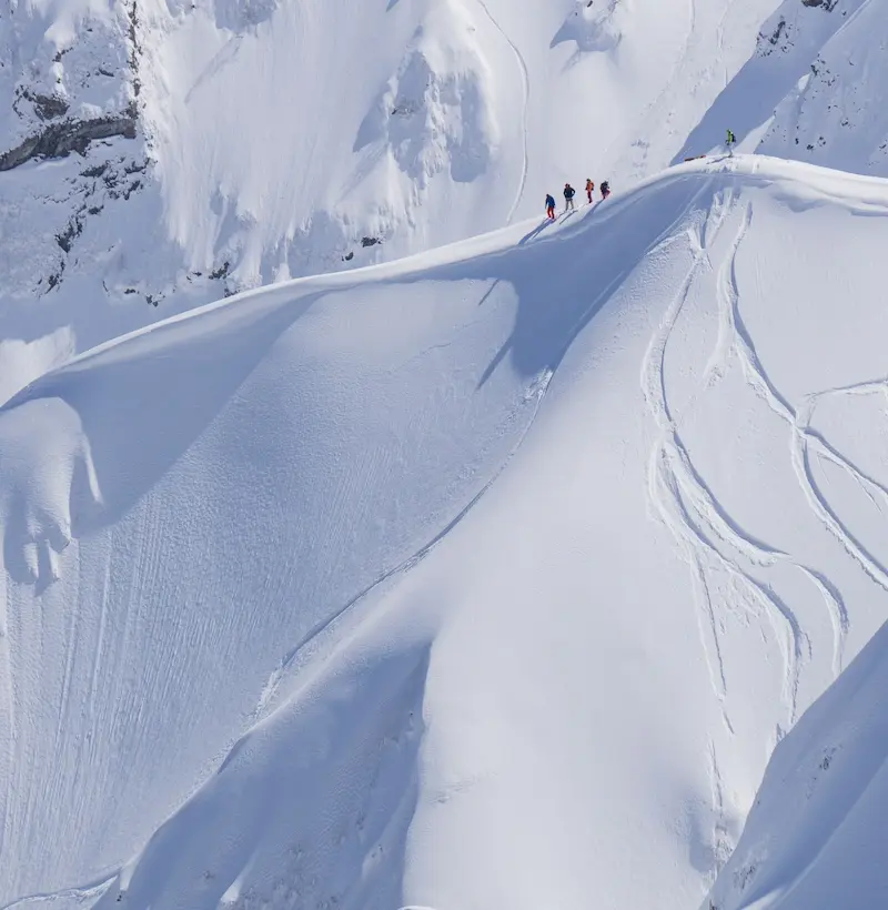 contacto sistemas health safety Montaña nevada con cuatro personas andando por la nieve